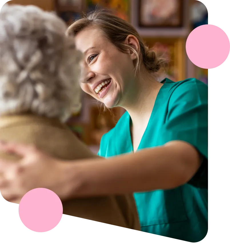 A care worker smiling whilst providing support for a client with dementia.